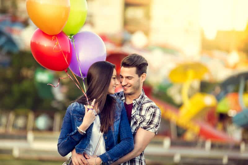 Romantic couple with balloons at an amusement park