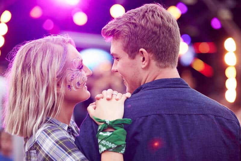 Couple looking at each other in the crowd at music festival.